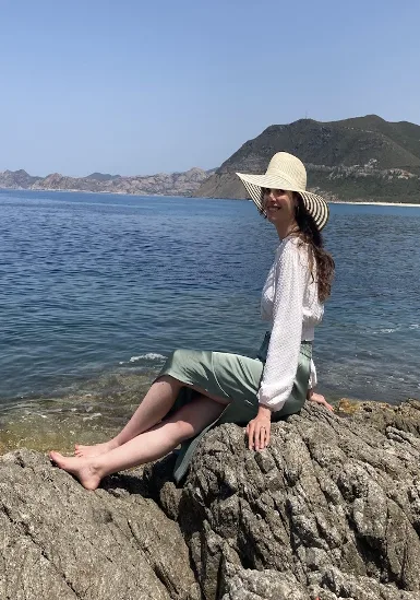 Anne sitzt barfuß auf Felsen am Meer